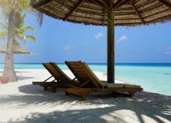 2 empty deck chairs on a beach overlooking the ocean.