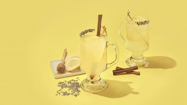 Yellow background with hot toddy's, lemons, honey, and cinnamon sticks