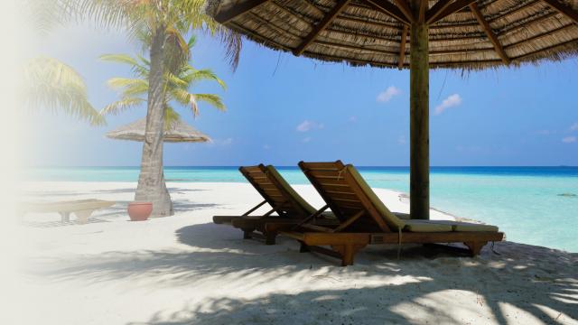 2 empty deck chairs on a beach overlooking the ocean.