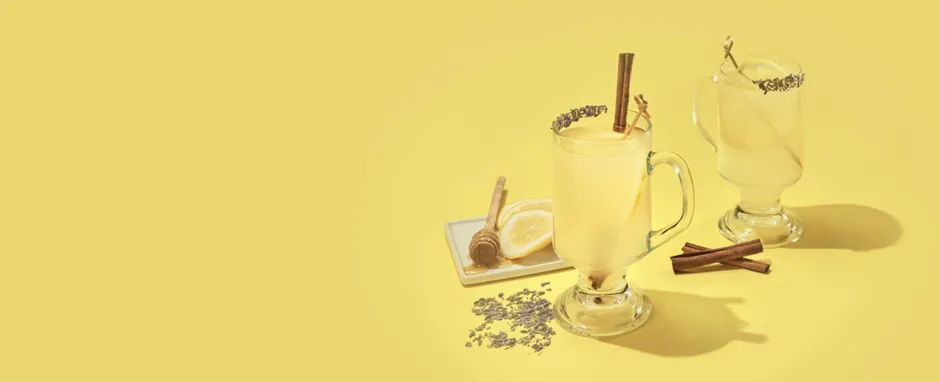 Yellow background with hot toddy's, lemons, honey, and cinnamon sticks