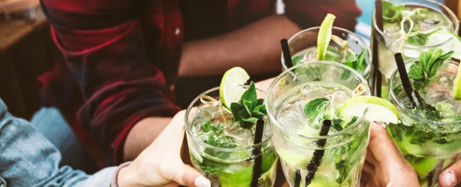 A group of friends cheersing with Fresh Cucumber Gin Mojitos