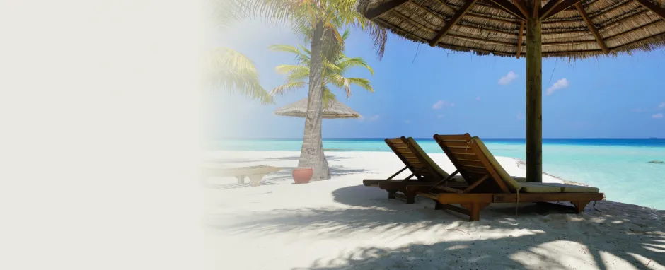 2 empty deck chairs on a beach overlooking the ocean.