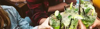A group of friends cheersing with Fresh Cucumber Gin Mojitos